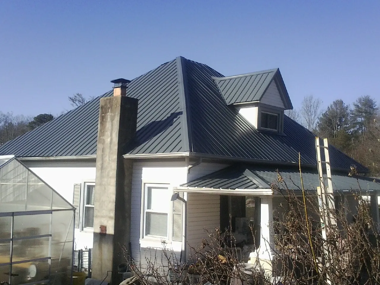 Dark blue standing seam metal roof on a white farmhouse with dormer — Slate & Tile Roof Repair by Roofing Brothers in Nehalem