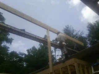 Carpenter setting a ridge beam over a new addition frame — Ice Dam Removal by Roofing Brothers in Nehalem