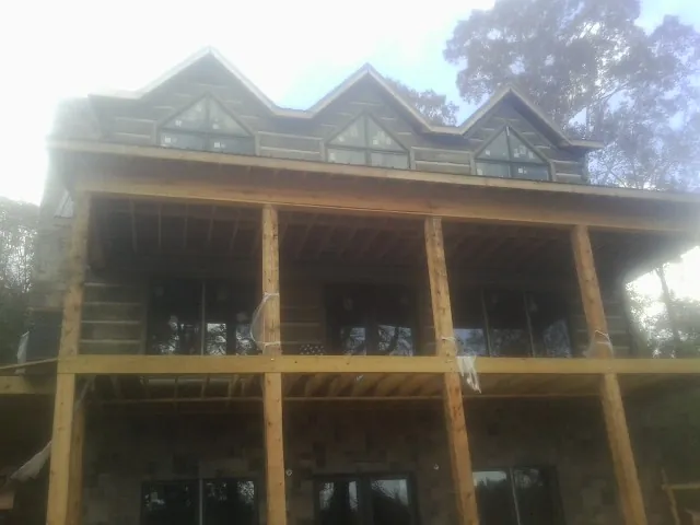 Dormers and porch framing on a large log home under construction — Roof Coating work by our crew in Nehalem