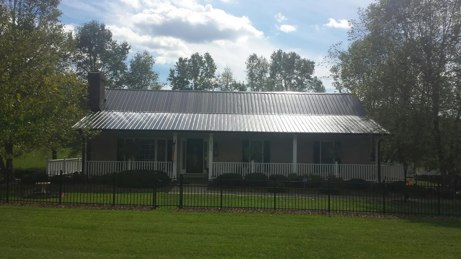 Gray metal roof on a brick ranch with a full width front porch — Gutter Guard Installation work by our crew in Nehalem