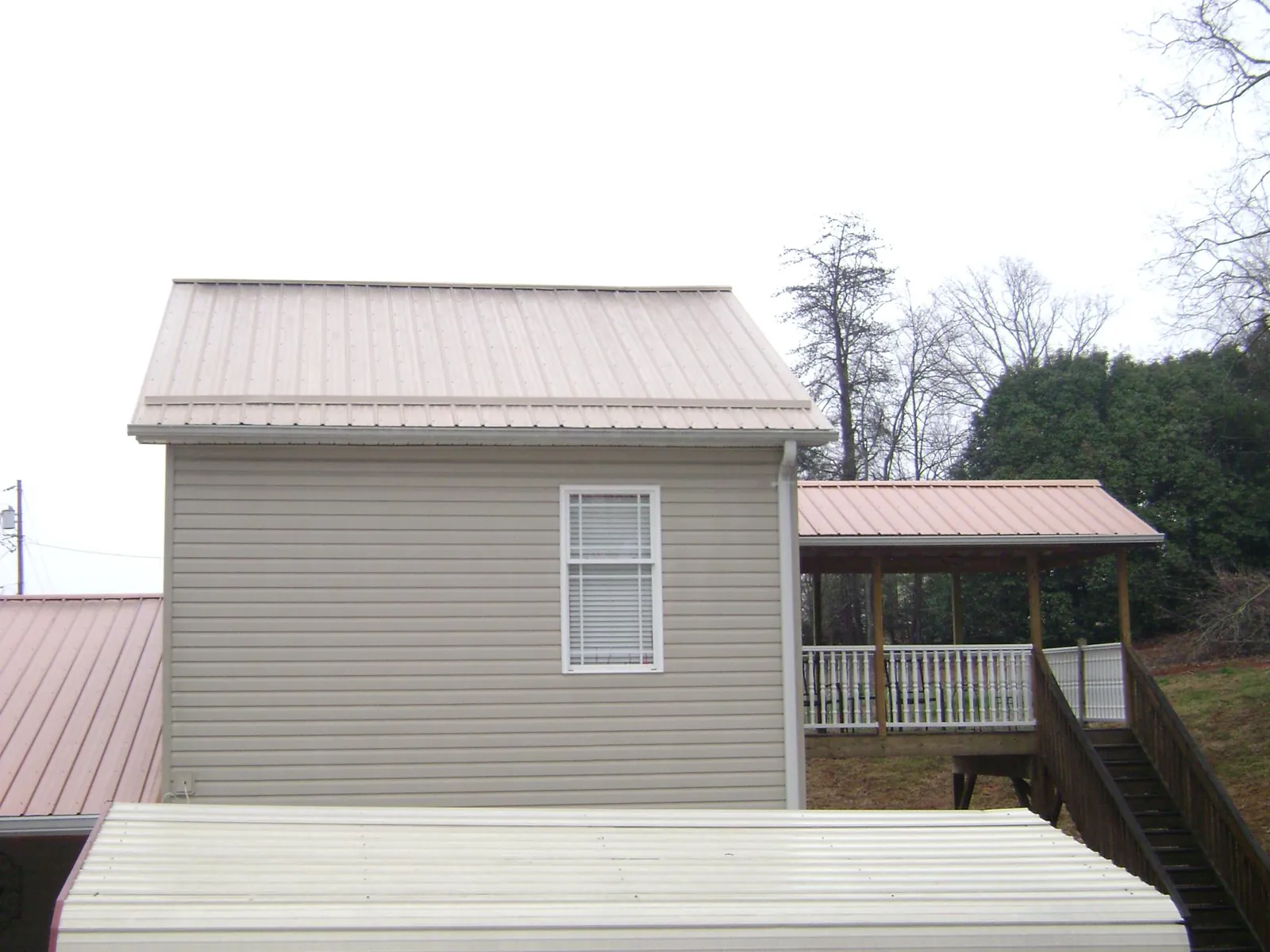 Tan metal roofs on a two story addition and attached porch, from a Roof Replacement job in Nehalem