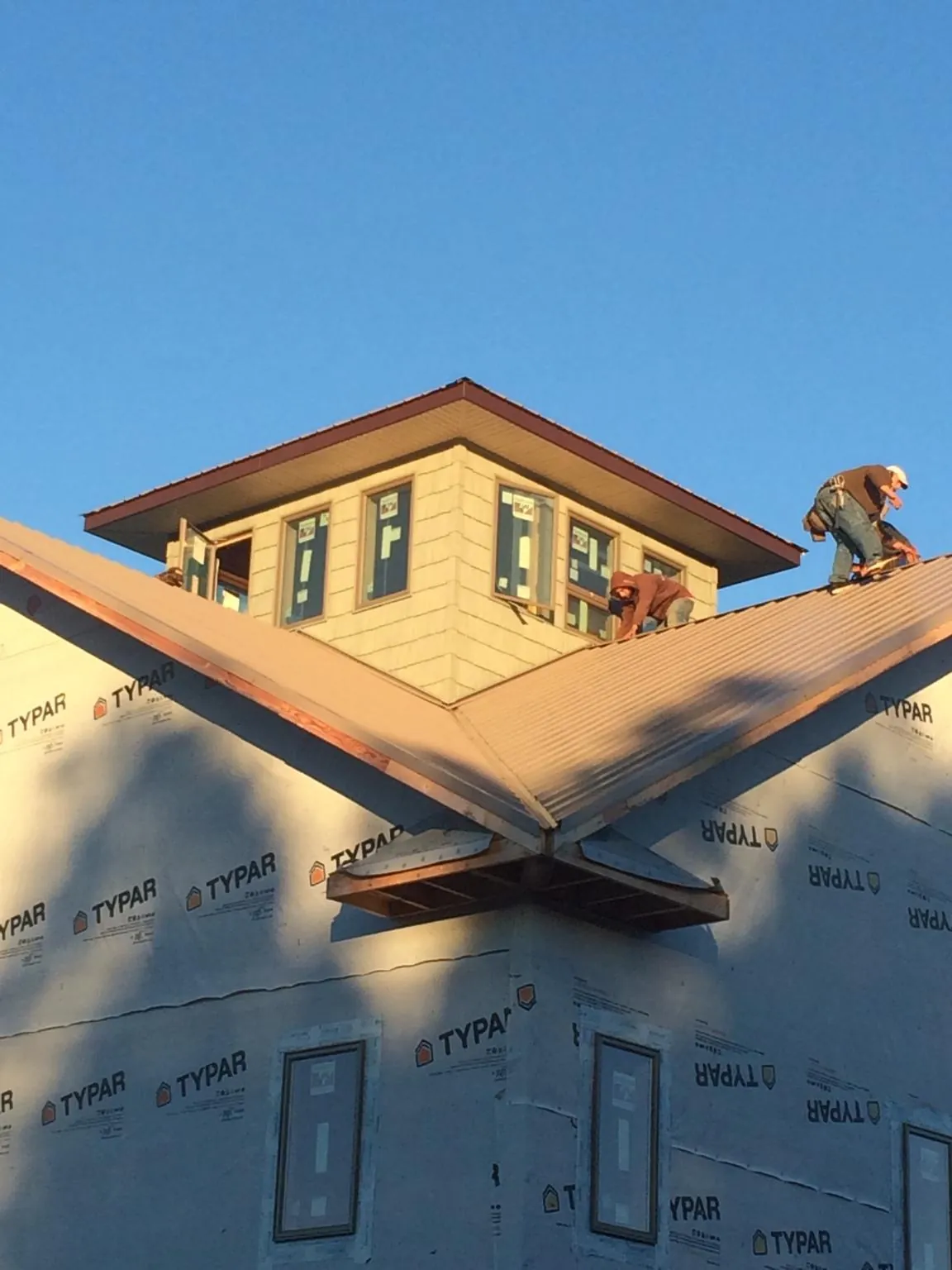 Roofers working around a rooftop cupola on a new metal roof at sunset — Roof Waterproofing in Nehalem by Roofing Brothers